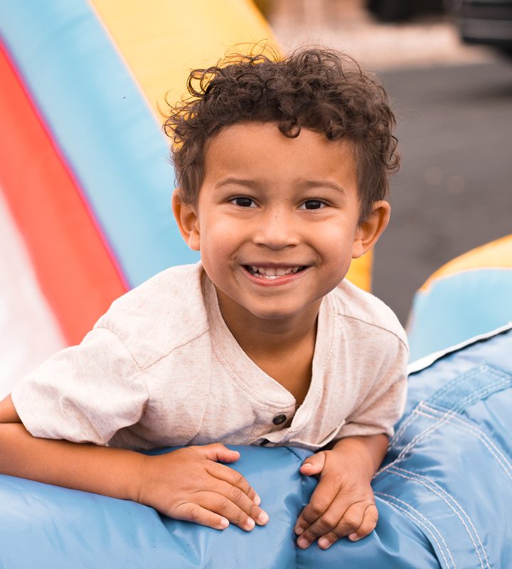 A smiling boy climbing a bounce house